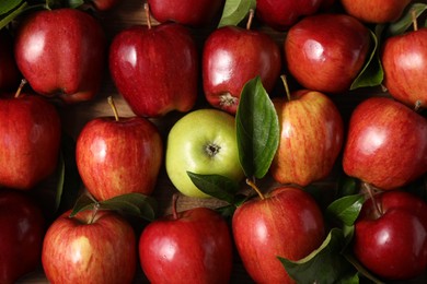 Photo of Fresh ripe apples with leaves on wooden table, flat lay