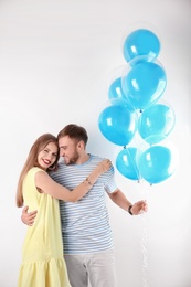 Young couple with air balloons on white background