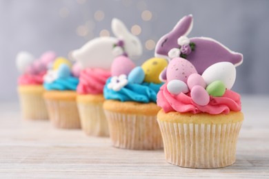 Photo of Tasty decorated Easter cupcakes on wooden table, closeup. Space for text