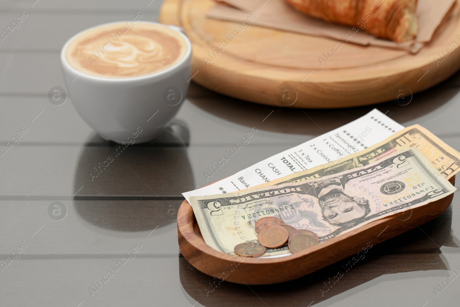 Photo of Tips, receipt and cup with coffee on wooden table