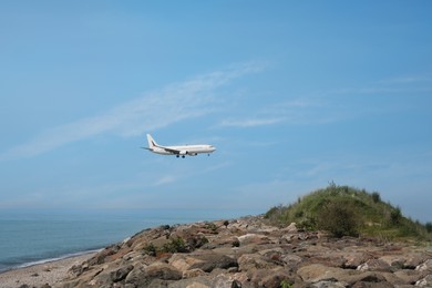 Photo of Airplane flying in blue sky over sea. Space for text