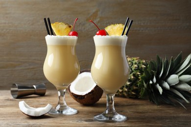 Photo of Tasty Pina Colada cocktail and ingredients on wooden table