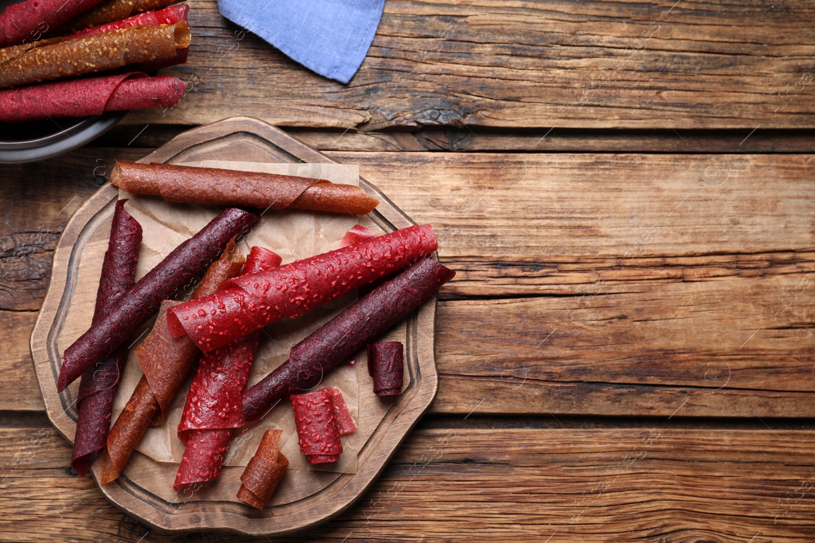 Photo of Delicious fruit leather rolls on wooden table, flat lay. Space for text