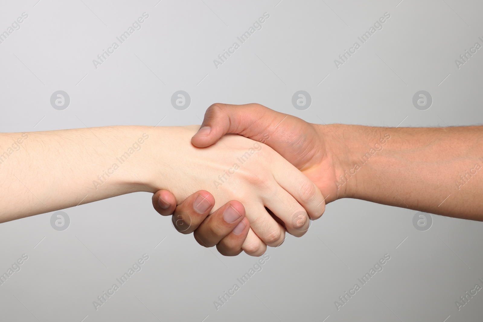 Photo of International relationships. People shaking hands on light grey background, closeup