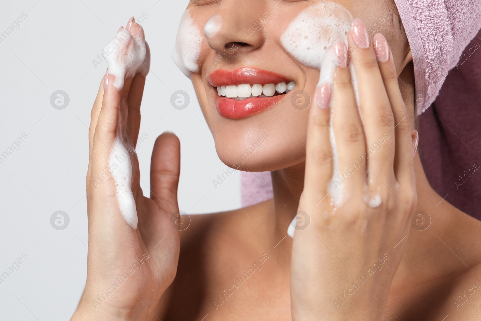 Photo of Beautiful woman applying facial cleansing foam on white background, closeup