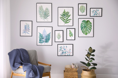 Beautiful paintings of tropical leaves on white wall in living room interior