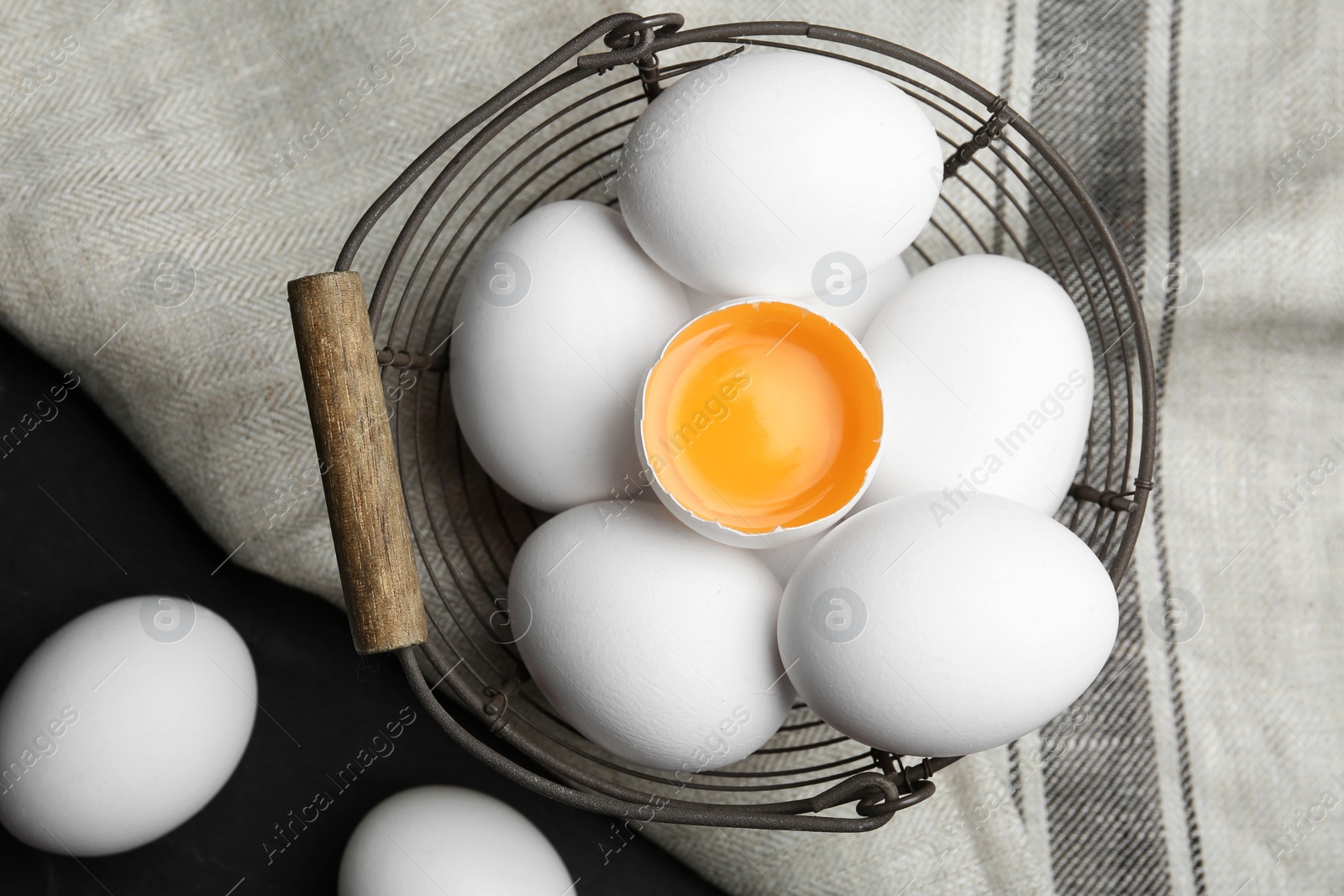 Photo of Many raw chicken eggs in metal basket on table, flat lay