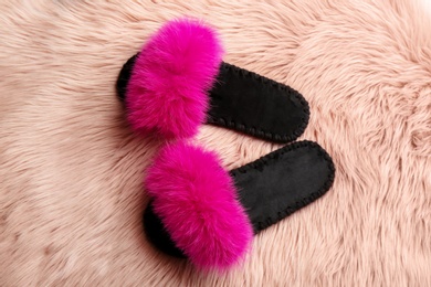Photo of Pair of soft slippers on pink faux fur, flat lay