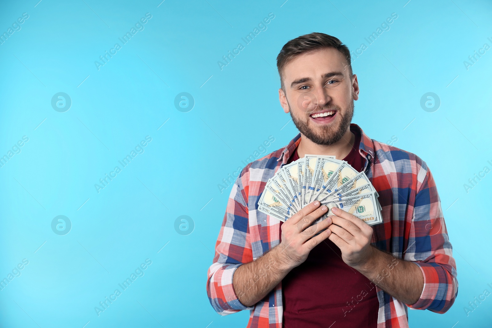 Photo of Portrait of happy young man with money on color background. Space for text