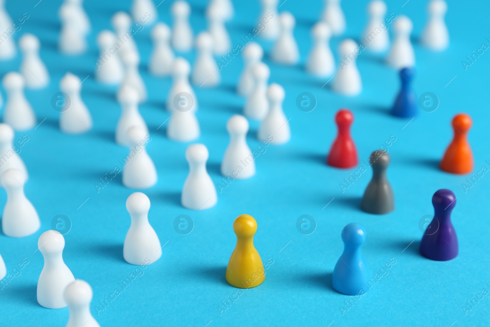 Photo of Colorful pawns on light blue background. Social inclusion concept