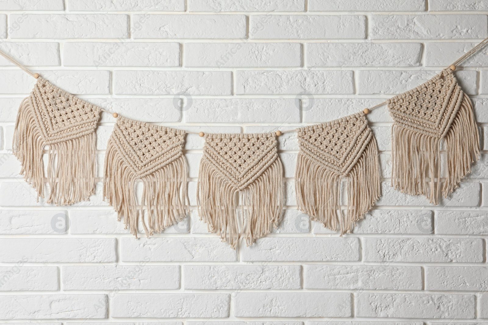 Photo of Stylish macrame hanging on white brick wall