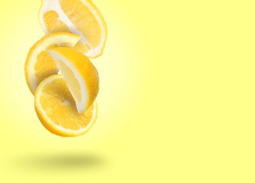 Image of Cut fresh lemons falling on light yellow background, space for text