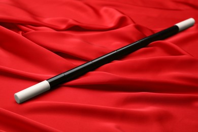Photo of Beautiful black magic wand on red fabric