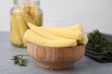 Tasty fresh yellow baby corns in bowl on grey table