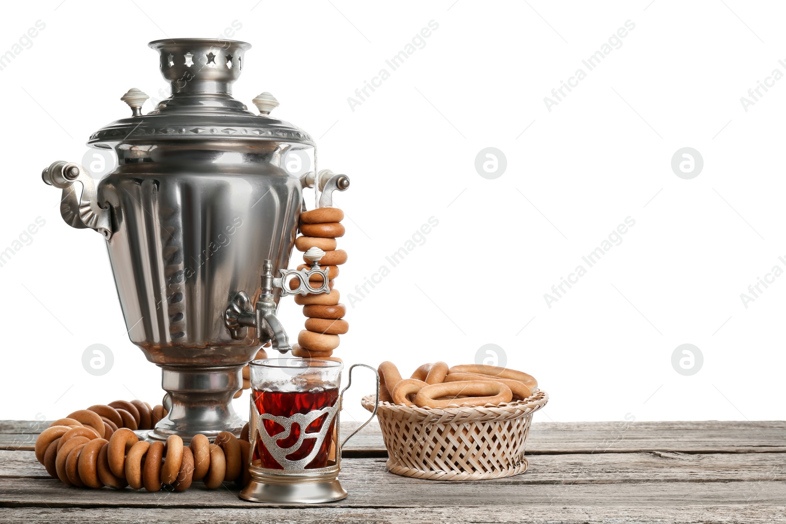 Photo of Composition with hot tea and delicious ring shaped Sushki (dry bagels) on wooden table against white background, space for text
