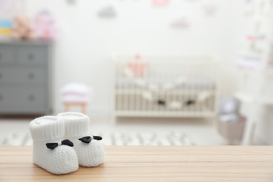 Photo of Small baby booties on wooden table in room. Space for text