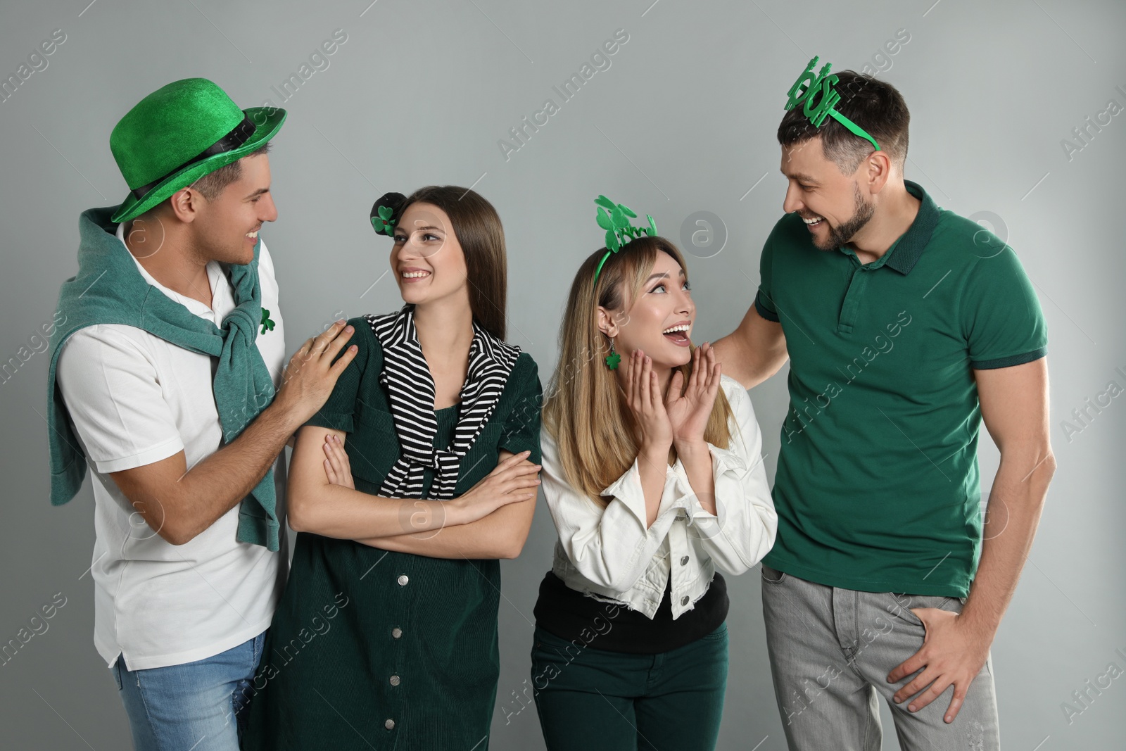Photo of Happy people in St Patrick's Day outfits on light grey background