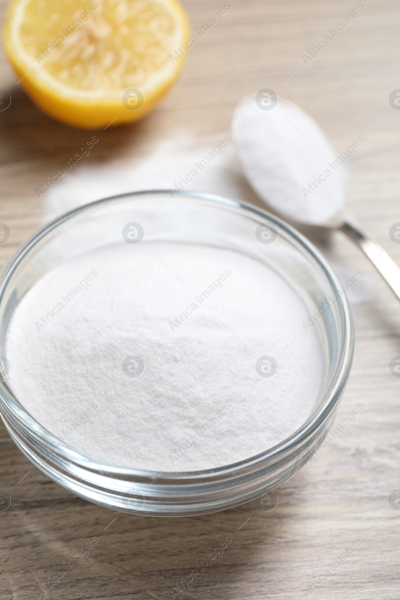 Photo of Baking soda and lemon on wooden table, closeup