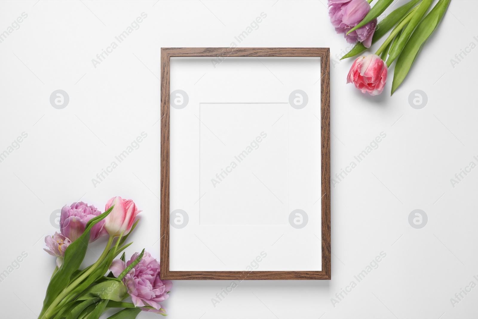 Photo of Empty photo frame and beautiful tulip flowers on white background, flat lay. Space for design