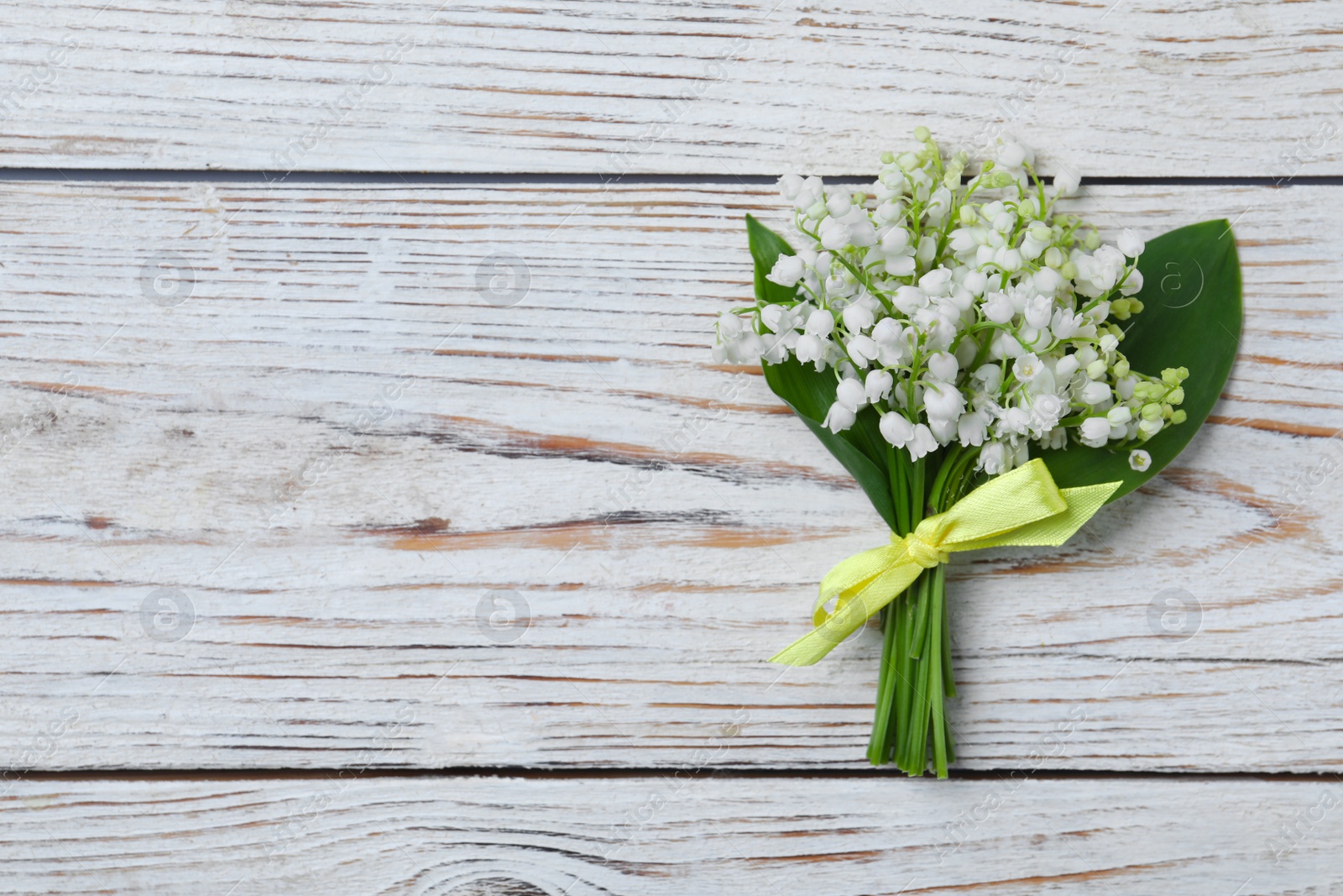 Photo of Beautiful lily of the valley flowers on white wooden table, top view. Space for text