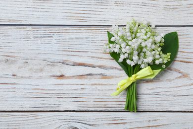 Photo of Beautiful lily of the valley flowers on white wooden table, top view. Space for text