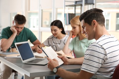 Young people discussing group project at table in library