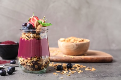 Photo of Delicious acai dessert with granola and berries served on grey table. Space for text