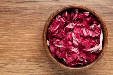 Photo of Cut radicchio in bowl on wooden table, top view