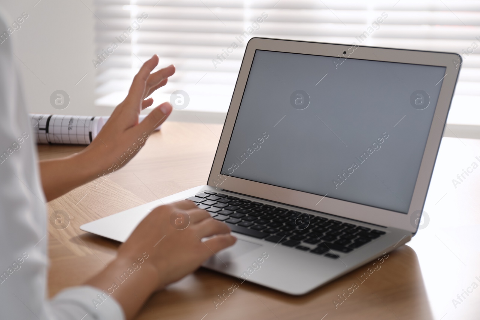 Photo of Woman using video conference to communicate with her coworkers at wooden table, closeup