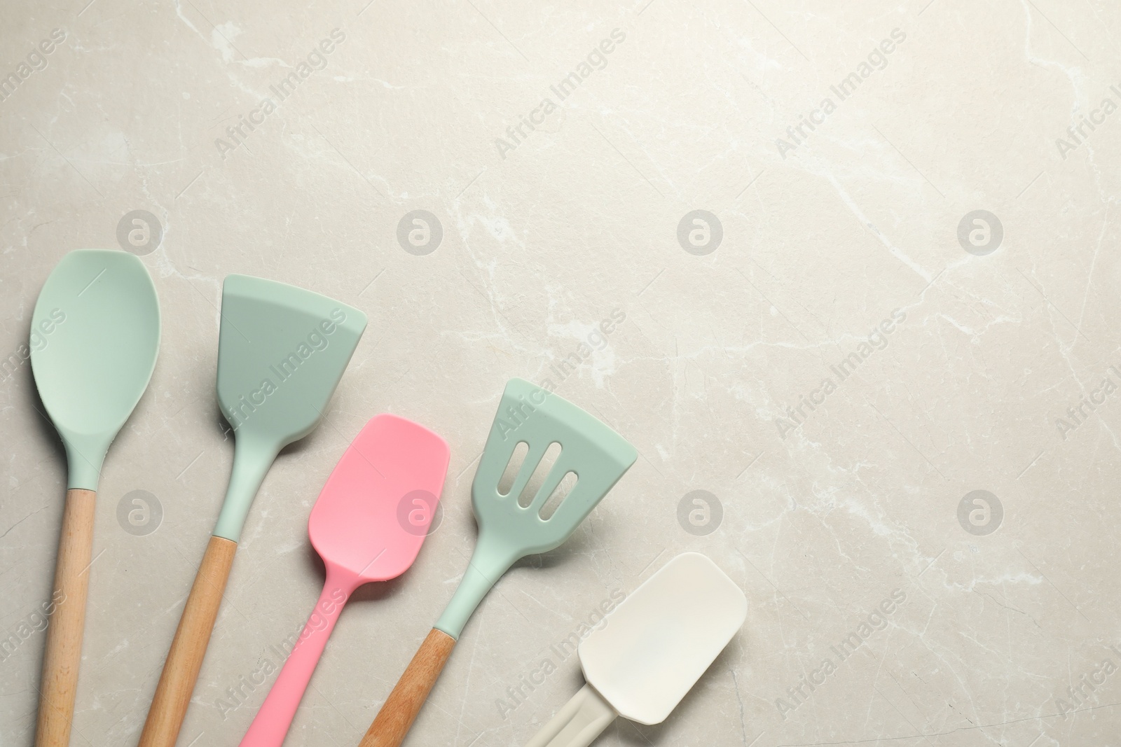 Photo of Different spatulas on light marble table, flat lay. Space for text