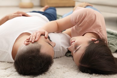 Affectionate young couple spending time together on soft carpet at home
