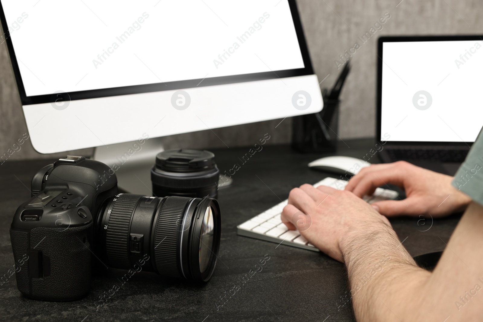 Photo of Photographer working on computer at dark table with camera, closeup