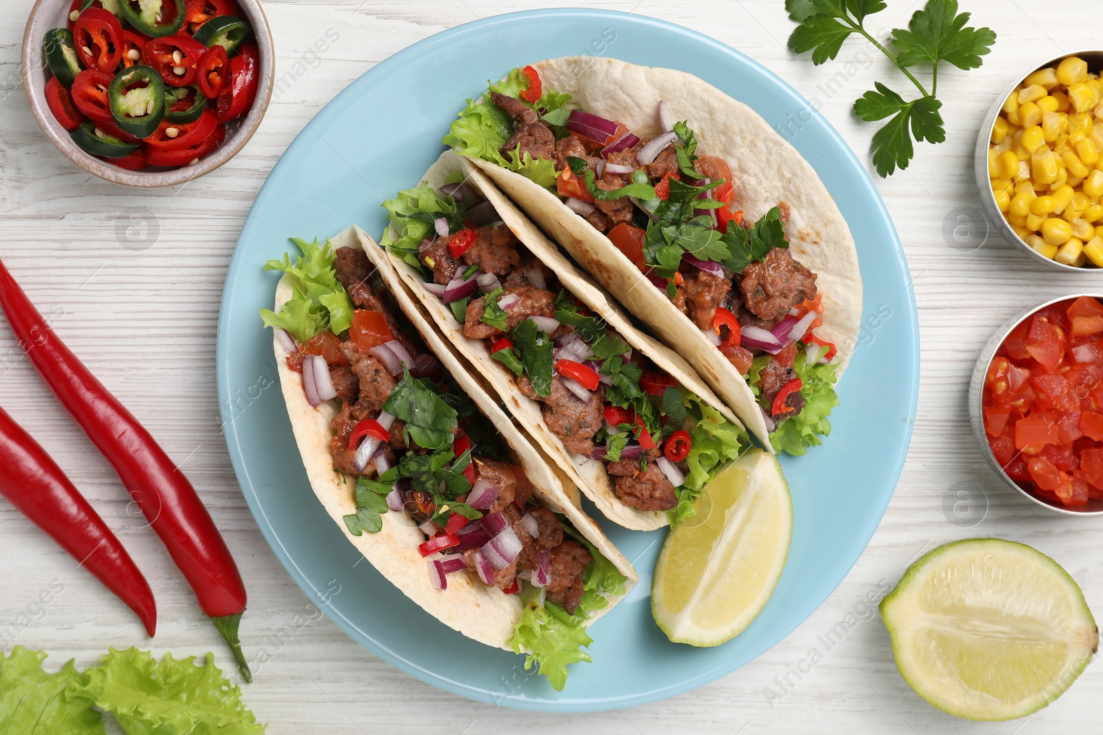 Photo of Delicious tacos and ingredients on wooden table, flat lay