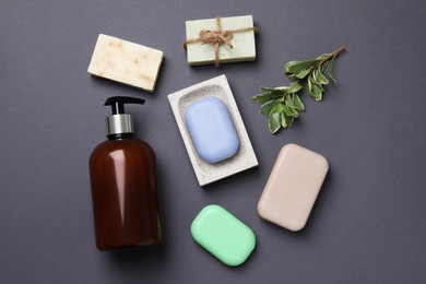 Photo of Soap bars and bottle dispenser on black background, flat lay