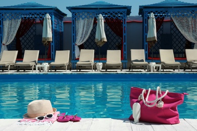 Beach accessories on wooden deck near swimming pool. Space for text