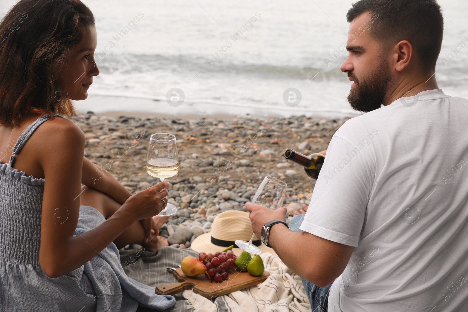 Photo of Young couple having picnic on beach near sea