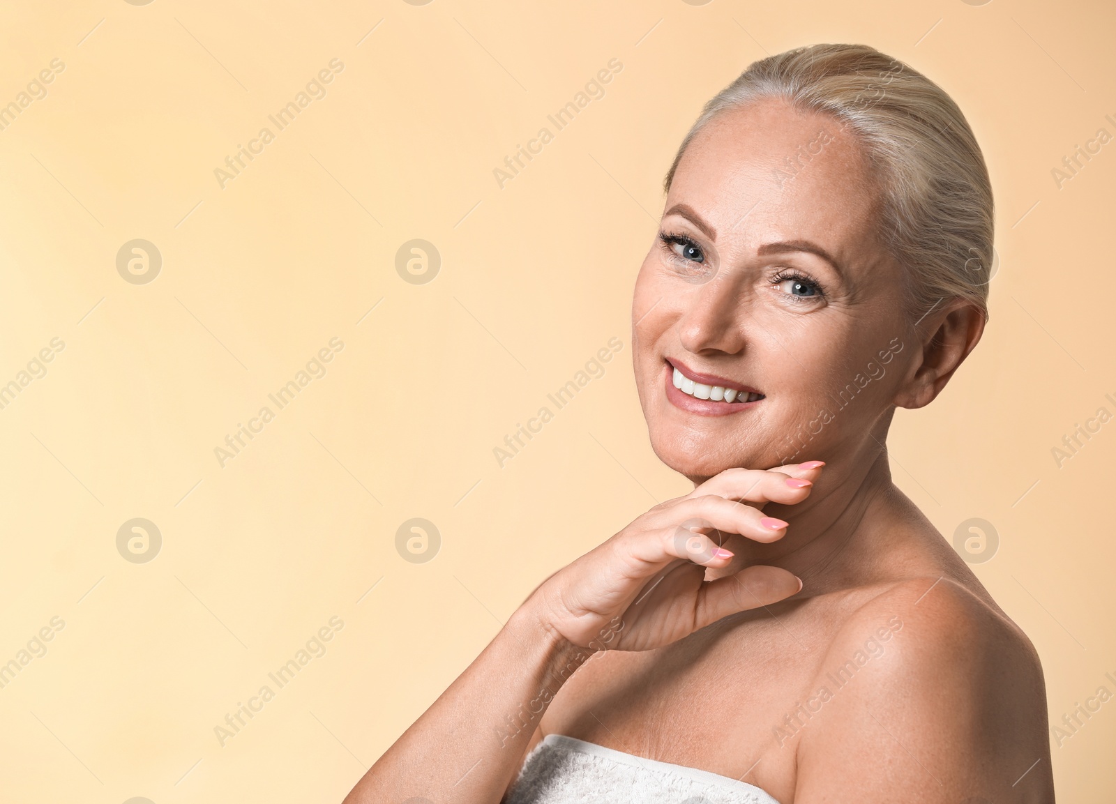 Photo of Portrait of beautiful mature woman with perfect skin on beige background. Space for text