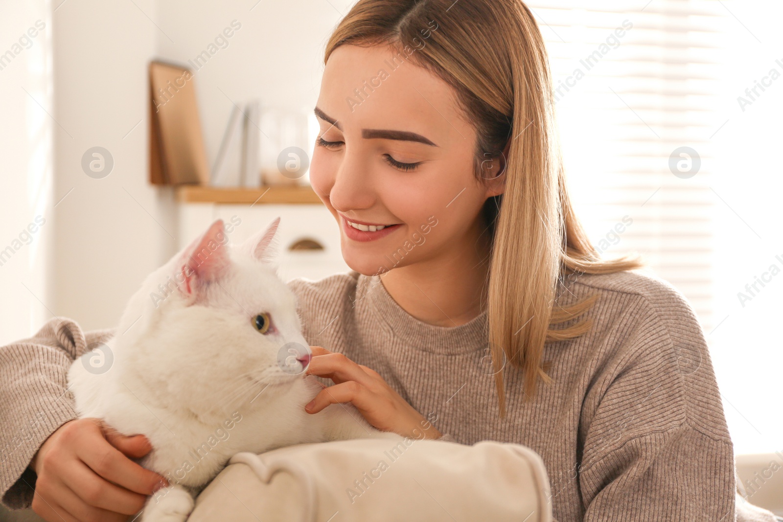 Photo of Young woman with her beautiful white cat at home. Fluffy pet