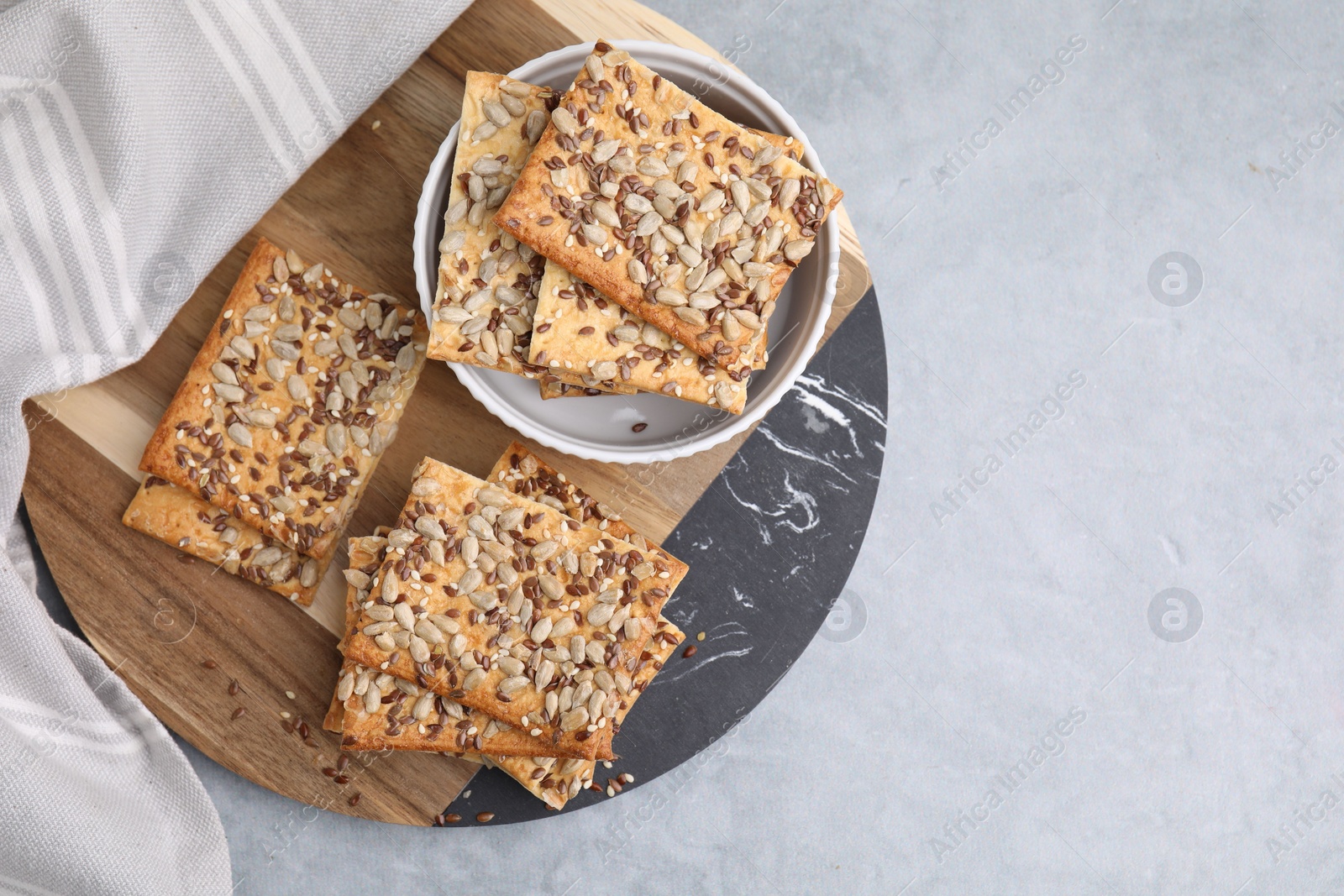 Photo of Cereal crackers with flax, sunflower and sesame seeds on grey table, top view. Space for text