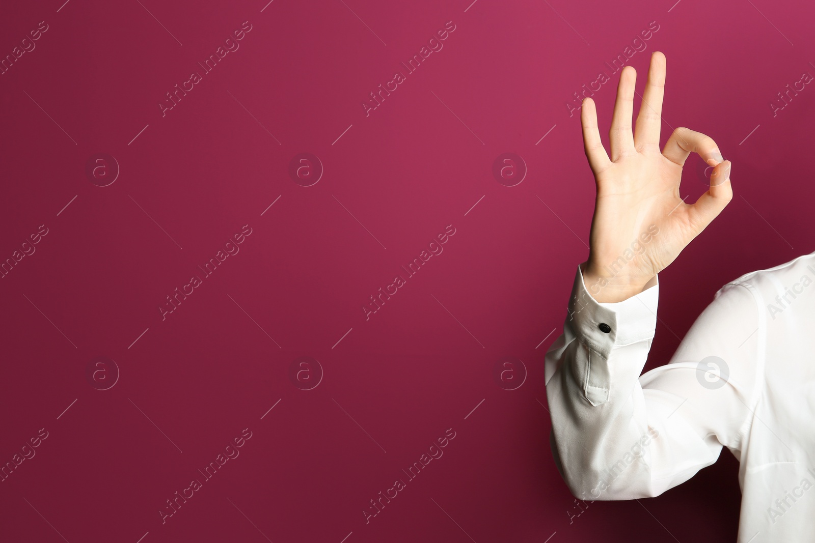 Photo of Young woman showing OK gesture on color background. Space for text