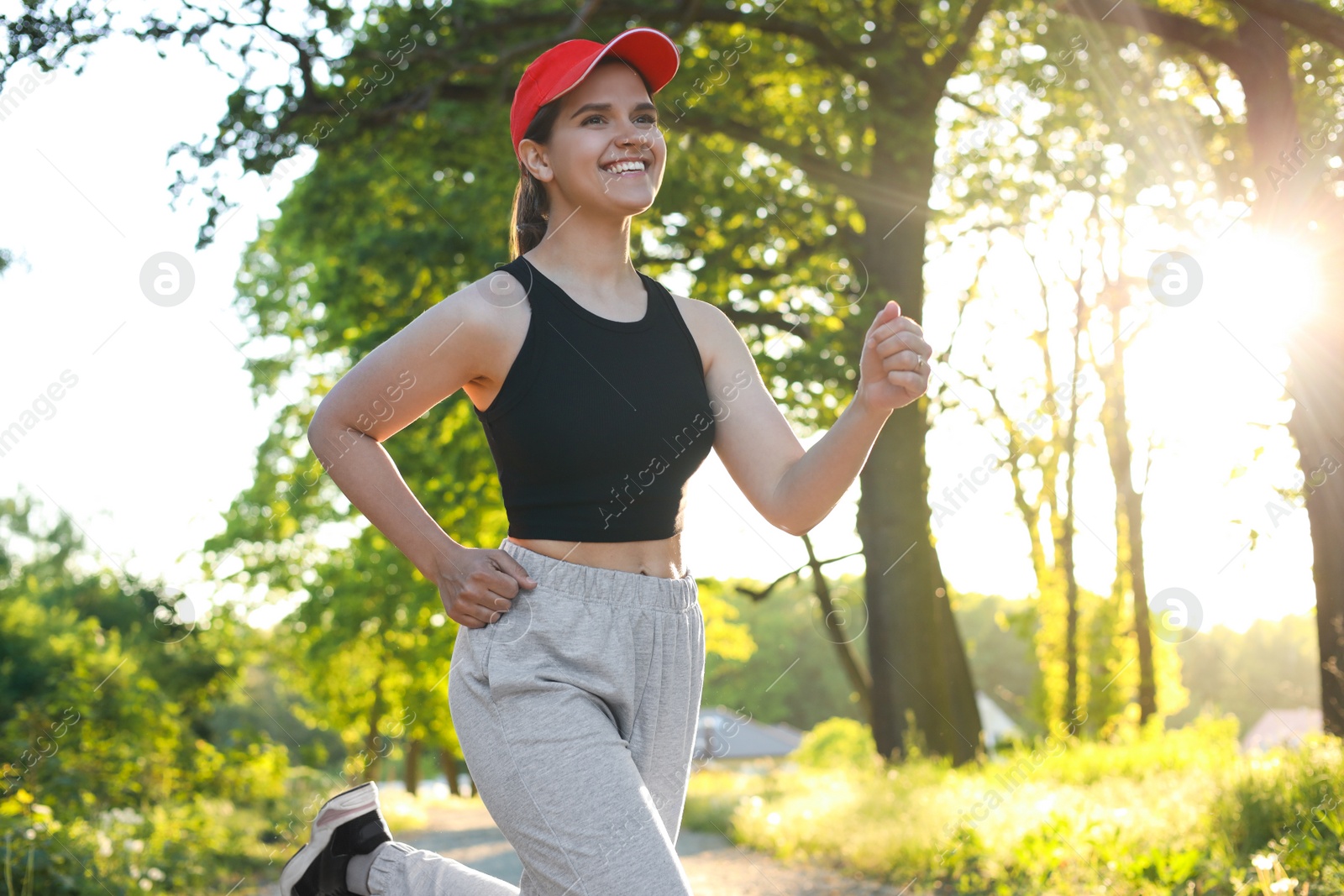 Photo of Young woman with cap running outdoors in morning