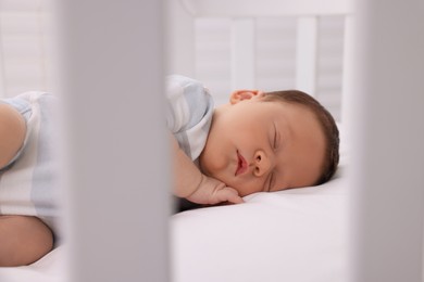 Cute newborn baby sleeping on white blanket in crib