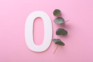 Paper number 0 and eucalyptus branch on pink background, flat lay