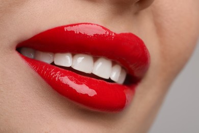 Photo of Young woman with perfect lips makeup on light background, closeup