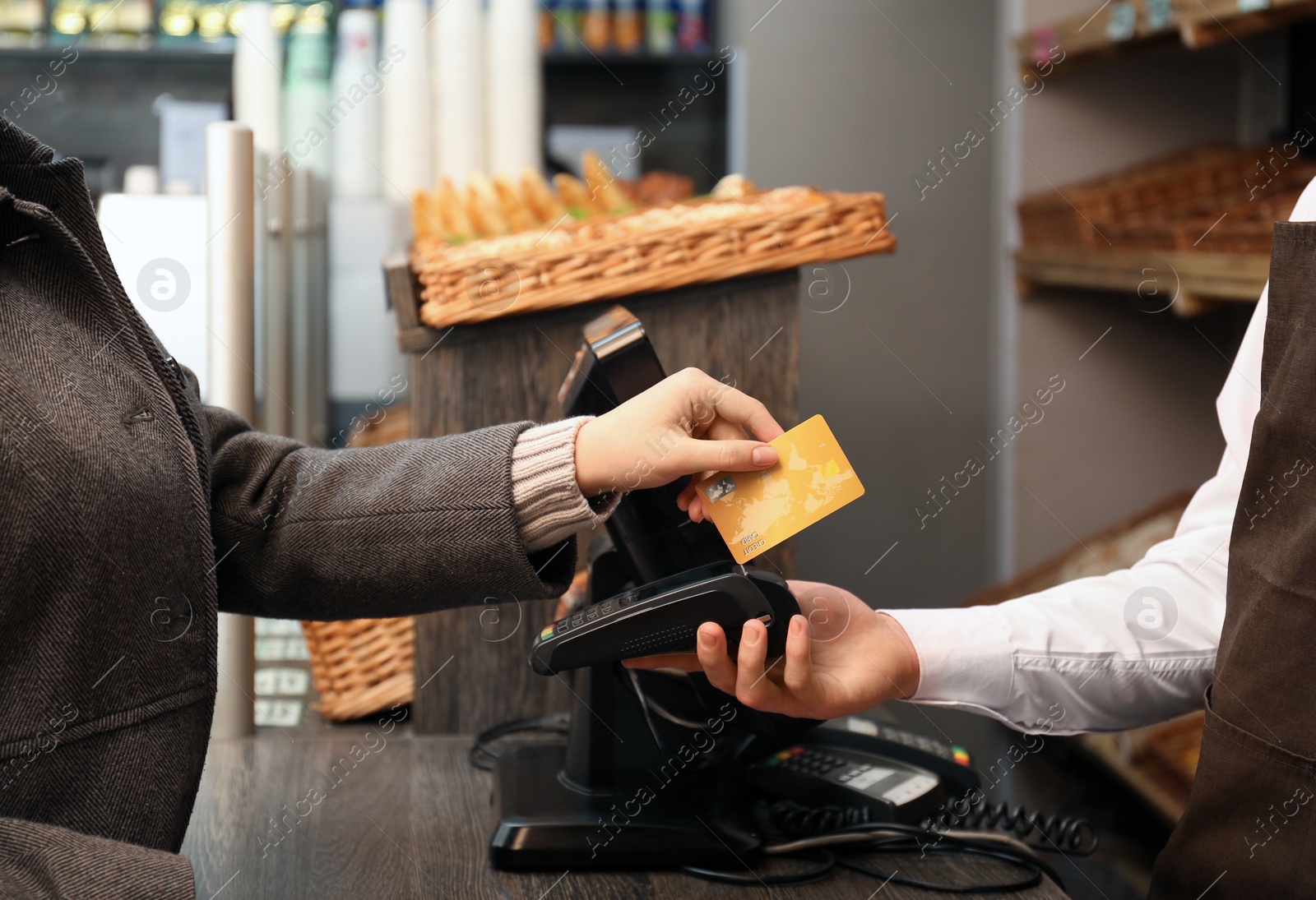 Photo of Woman with credit card using payment terminal at shop