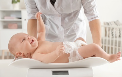 Doctor weighting baby on scales in light room