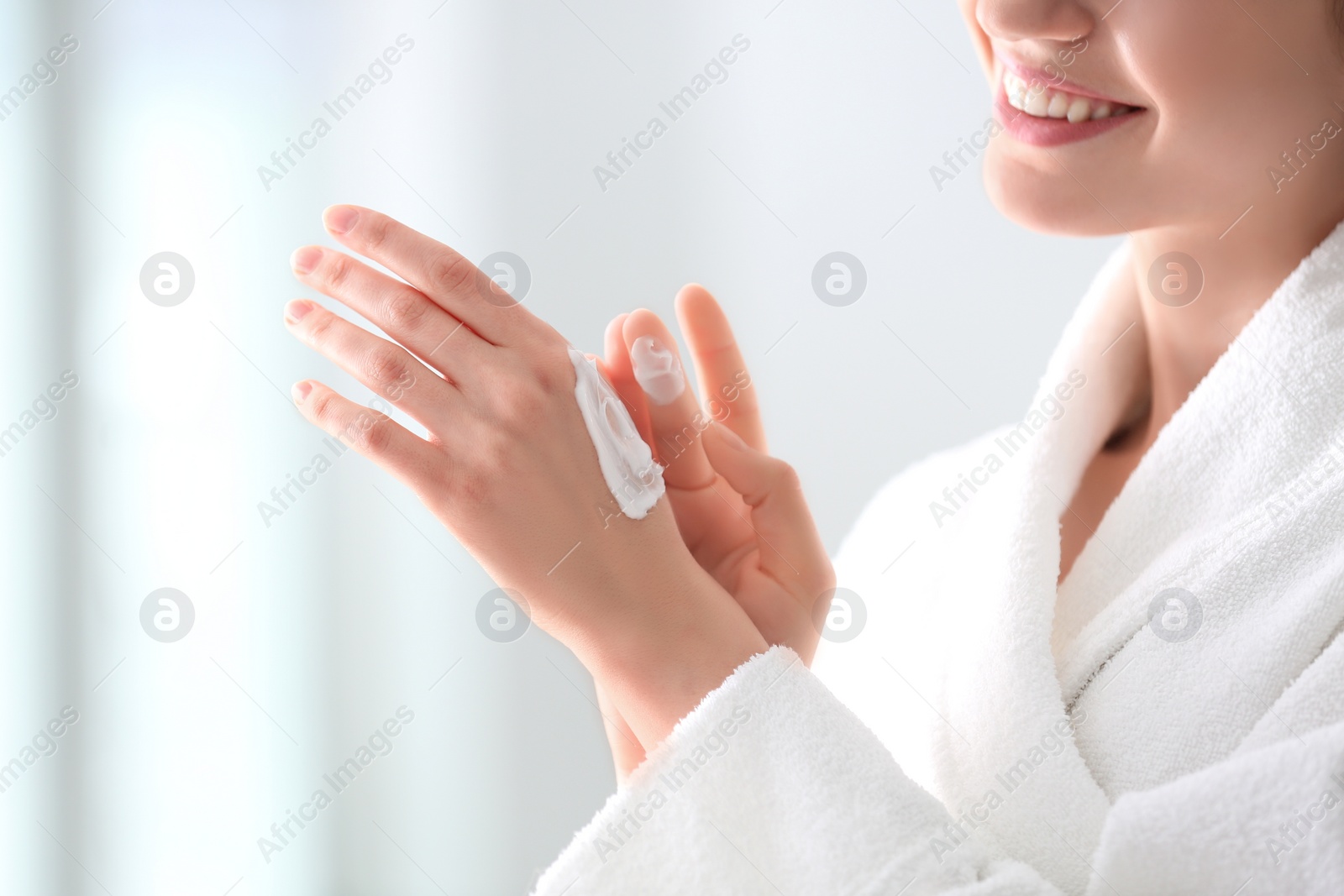 Photo of Young woman applying hand cream at home, closeup