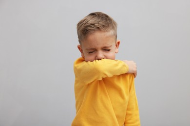 Photo of Sick boy coughing on gray background. Cold symptoms