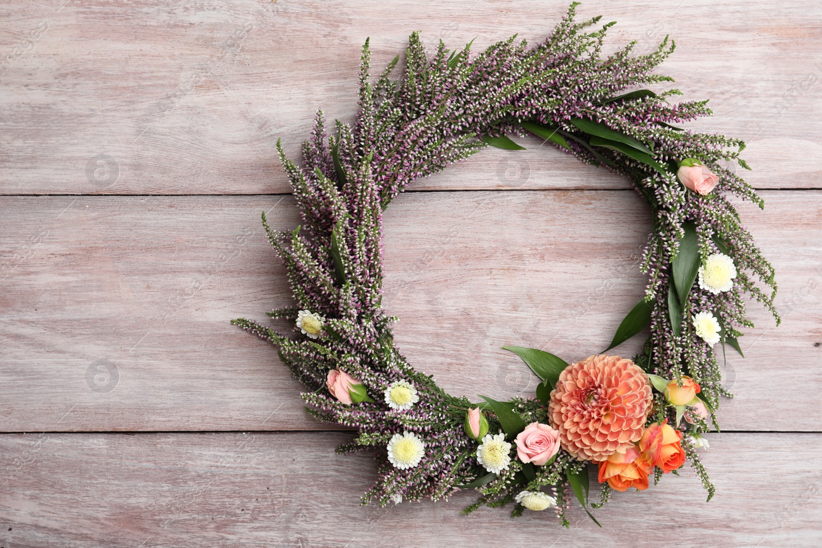 Photo of Beautiful autumnal wreath with heather flowers on light wooden background, top view. Space for text