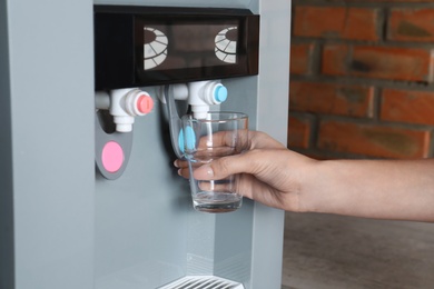 Photo of Woman filling glass from water cooler, closeup